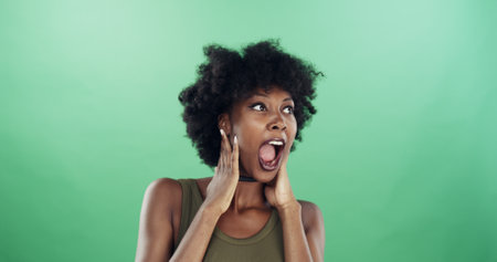 Surprise, winner and black woman in studio, excited and facial expression on green background. African person, shocked and happy model with announcements, energy and victory with omg, wow and emojiの写真素材