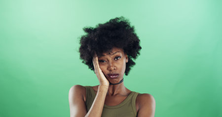 Bored, portrait and black woman in studio with annoyed, fatigue or thinking facial expression. Mockup space, upset and African female person with exhaustion, tired or moody face by green background.の写真素材