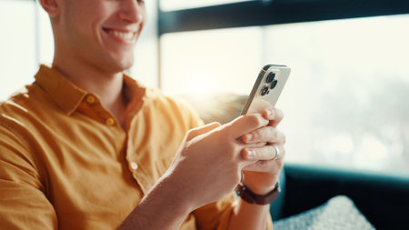 Playing, video games and man with smartphone, house and entertainment for gamer with tech in lounge. Chilling, player and person with mobile app for virtual sport, smile or online for digital fantasyの写真素材