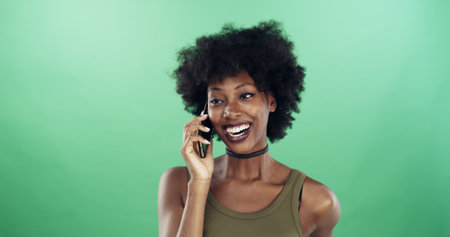 Phone call, happy and black woman in studio for communication, contact or social networking. Smile, cellphone and African female person with connectivity by green background with mockup space.の写真素材