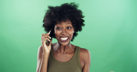 Phone call, excited and black woman in studio for communication, contact or social networking. Happy, cellphone and African female person with connectivity by green background with mockup space.の写真素材