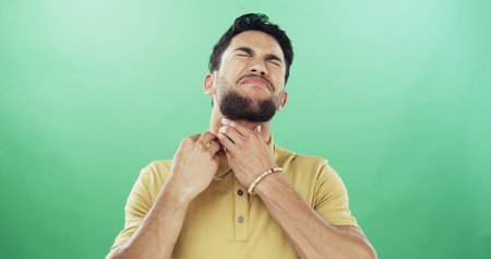 Itchy, neck and scratch with man on green background for allergic reaction or skin irritation. Dermatitis, eczema or inflammation and person in studio with rash or symptoms of medical conditionの写真素材