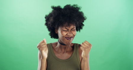 Frustration, stress and black woman in studio with reaction for mistake, fail or crisis with anger. Annoyed, emotion and African person with regret for rage, fear or mental health by green backgroundの写真素材