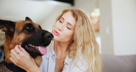 Home, woman and kiss for dog, petting and affection for german shepherd in lounge and rescue animal. Care, owner and person with domestic canine, bonding and love for furry companion in apartmentの写真素材