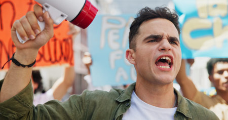 Angry, rally or man with bullhorn in street for announcement, human rights or power. People, revolution and crowd in protest with megaphone for activism, justice or community for change in governmentの写真素材
