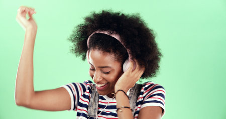 Green background, smile and woman with headset for dancing, movement and listening to audio track. African female person, model and energy with rhythm for podcast, hip hop and music in studio mockupの写真素材