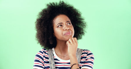 Black woman, thinking and green screen for choice, option and education comparison. Student person, question and idea on chroma key for opportunity, problem solving and decision with doubt in studioの写真素材