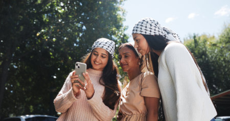 Phone, keffiyeh and activist with friends in city for protest post, human rights and social justice. Gaza relief, community and online support with women outdoor for genocide awareness and palestineの写真素材