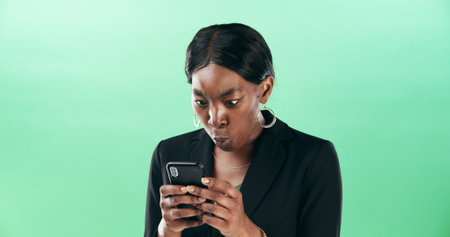 Black woman, smartphone and business announcement for shock in studio, feedback and alarm for web error. Green background, wow or professional communication alert with mobile app, fake news or glitchの写真素材