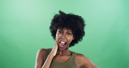 Portrait, funny face and black woman in studio, expression and confident personality on green...