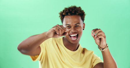 Excited, dance and black man with portrait, music and comedy with smile in studio. Isolated, green background and happy male model with celebration, energy and freedom with hip hop for weekend funの写真素材