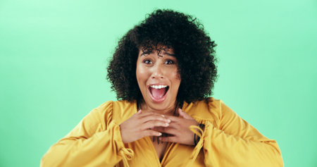 Excited, surprise and portrait of woman in studio with winning lottery, prize or promotion. Happy, sale and person with announcement for bonus with wow, omg or shock expression by green background.の写真素材