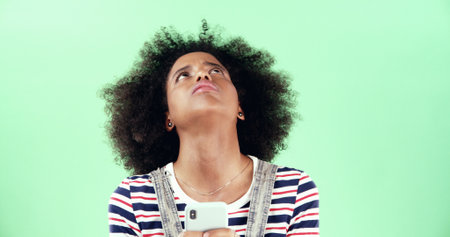 Frustrated, phone and news with woman in studio for college rejection, application fail and thinking. Scholarship crisis, tests result and portal login with person on green background for faqの写真素材