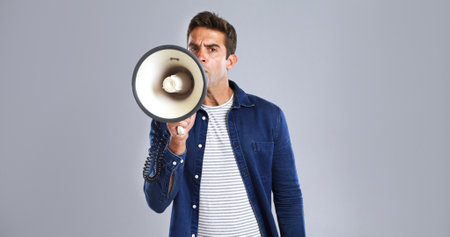Portrait, megaphone and man in studio, screaming or justice with protest on white background. Facial expression, person or model with bullhorn, frustrated or activism for human rights, noise or angryの写真素材