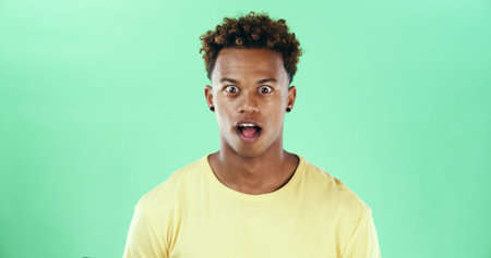 Black man, portrait or surprise in shock on green background for rumor or gossip in studio. Male...