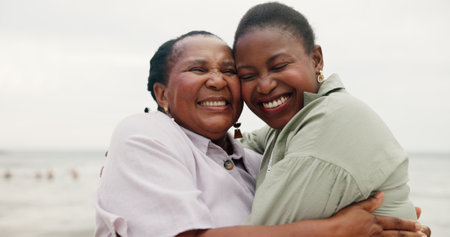 Smile, mother and daughter with hug on beach for travel, summer holiday and getaway. African family, laugh and embrace with mature woman, tropical vacation and bonding together for affection on tripの写真素材