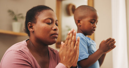 Praying, religion and black mother with child in home for worship, praise or spiritual wellness. Bonding, hope and African mom teaching boy kid with christian prayer in morning for gratitude in houseの写真素材