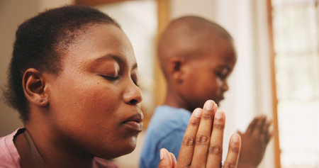 Praying, worship and black mother with kid in home for religion, praise or spiritual wellness. Bonding, hope and African mom teaching boy child with Christian prayer in morning for gratitude in houseの写真素材