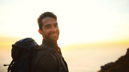 Hiking, sunrise and man with portrait on mountain for travel adventure, sightseeing and explore. Space, happy and person with backpack for trekking break, backpacker journey and relax at destinationの写真素材