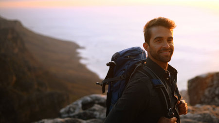Happy man, portrait or hiking on mountain sunset with backpack for outdoor adventure or journey. Male person, hiker or smile with bag or scenic view on cliff for trekking, fitness or travel on spaceの写真素材