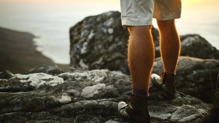 Legs, man and hiking with back view of ocean on vacation, holiday and adventure in nature. Rocks, shoes and person trekking on mountain for exploration, tourism and travel for hobby by cliff at seaの写真素材