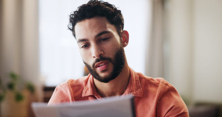 Reading, finance and man with paperwork in home for mortgage, loan payment and taxes. Worry,...