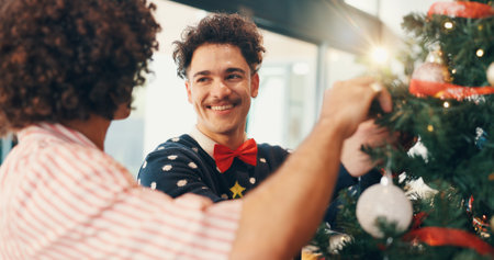 Christmas, smile and men with tree, help and bonding together with festive season. People, apartment and friends with Xmas event, home or celebration with tradition, holiday and decoration with breakの写真素材