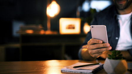 Hands, night and man in office, smartphone and message to contact, social media and communication. Person, closeup and employee in workplace, evening and cellphone with digital app for chattingの写真素材