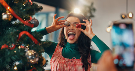 Christmas tree, funny and picture with woman and ornament for festive season, memory and decoration. Merry xmas, holiday and photography with silly person in living room of home for happy and baubleの写真素材