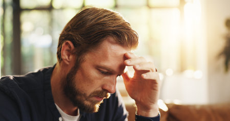 Stress, man and thinking with worry at house for bad decision, financial crisis or reflection. Disappointed, person or wonder for bankruptcy risk, remember mistake and regret choice with debt concernの写真素材