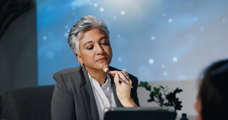 Mature woman, conference or presentation for public speaking, development seminar or business event. Convention, speech and workshop for corporate ceo in auditorium with assistant, makeup and helpの写真素材