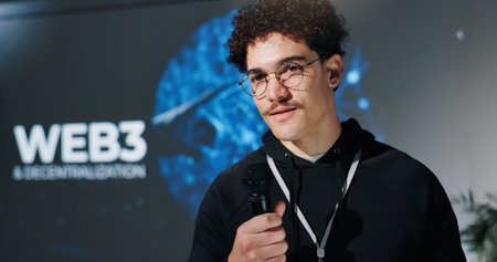 Business, seminar and speech with man in auditorium for presentation on web3 development. Mic, event and stage with speaker for intro to blockchain technology or decentralization of user experienceの写真素材