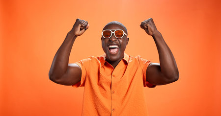 Winner, black man and fist pump for celebration in studio with sunglasses for fashion prize. Yes,...