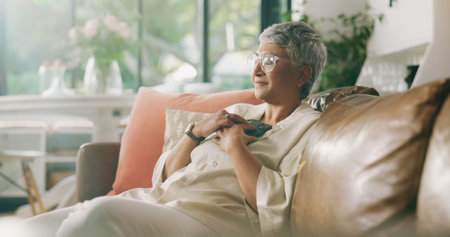 Smile, relax and phone with old woman on sofa for social media news, update and text message. Calm, reflection and online chat with senior person in living room of home for communication appの写真素材