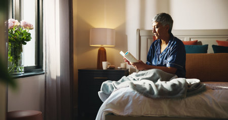 Reading, relax and book with old woman in bed for knowledge, literature self help study. Mindfulness novel, learning and retirement with senior person in bedroom of home for information and restの写真素材