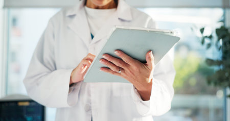 Hands, tablet and doctor in hospital for research, telehealth or online medical consultation. Healthcare, technology and physician woman with wellness app, website or internet schedule in clinicの写真素材