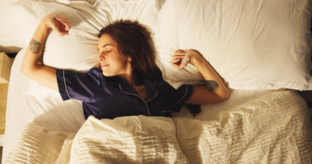 Comfortable, rest and sleeping with woman in bedroom for morning or weekend break and wellness. Above, exhausted and tired with person asleep in bed of apartment for dreaming or recovery from fatigueの写真素材