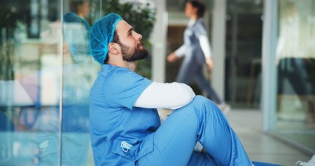 Sad, man and surgeon on floor at hospital with medical mistake, surgery fail and patient loss. Upset, male doctor and stress from bad news, wrong diagnosis and operation error with healthcare burnoutの写真素材