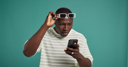 Surprise, smartphone and black man in studio, wow or announcement on green background. African...