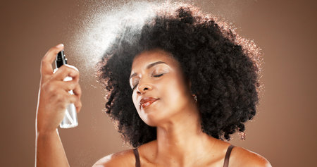 African woman, face mist and skincare in studio for hydration, beauty and facial treatment. Female...