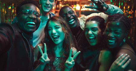 Selfie, peace sign and smile with friends at night club for social media, reunion and disco event. Happiness, celebration and photography POV with people at bar for culture, weekend and new yearsの写真素材