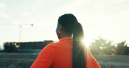 Fitness, running and back of woman in city for workout, training or activity in morning. Sports, break and female athlete with cardio exercise for marathon, race or competition practice in town.の写真素材