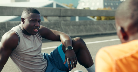 Friends, fitness and people with rest in road for running break, conversation or exercise recovery. Athlete, black men and talking on city bridge with burnout, marathon discussion or training fatigueの写真素材