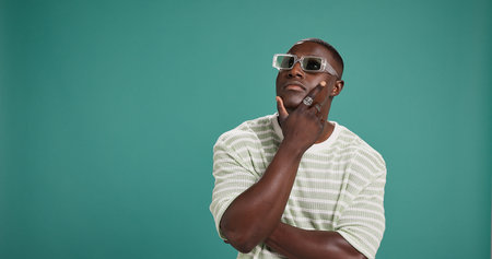 Black man, fashion and sunglasses with thinking, style and confidence on green studio background....