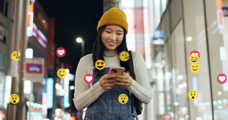 City, emoji and walking with influencer at night for interaction with social media followers. App, phone and reaction overlay with woman outdoor for late sightseeing or travel as content creatorの写真素材