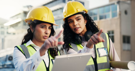 Pointing, civil engineer and women with blueprint, city and plan for property development or design. Architecture, collaboration and people with clipboard for construction, conversation and outdoorの写真素材