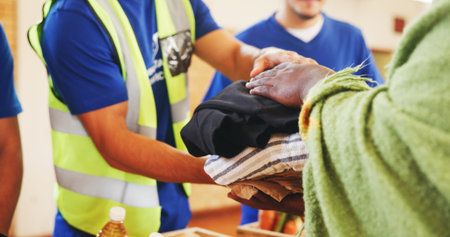 Clothes, help or hands with donation for homeless person, social project or community relief. Charity, group or people giving blankets for humanitarian aid, distribution or winter with support at NGOの写真素材