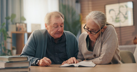 Senior couple, bible and reading in home together for religious study, spiritual bonding and faith. Retirement, old people and Holy book in living room to worship God, Christian praise and scriptureの写真素材