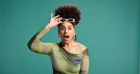 Shocked, fashion and happy woman in studio with mouth open, wow and alert for announcement. African person, surprise and portrait for drama, discount or gossip on green background with spaceの写真素材