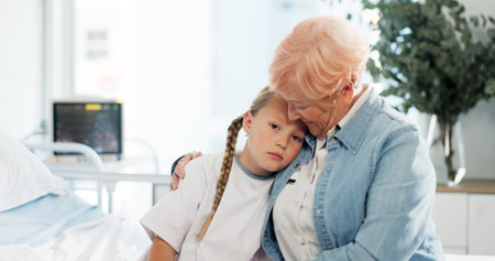 Hug, healthcare and sad with grandmother and child in hospital for support, pediatric patient and care. Medical, empathy and depression with senior person and kid for family comfort and trustの写真素材